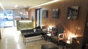 En moderne hotellobby med reception, siddeområde og kunst på væggene.
