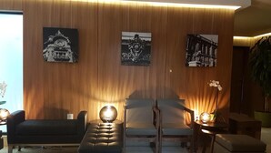 En moderne stue med sofa, skammel og lænestole, træpaneler og sort-hvid kunst.