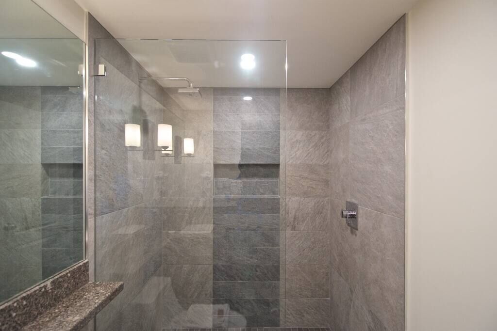 A modern bathroom with a glass shower enclosure, a marble countertop, and a wall-mounted towel rack.
