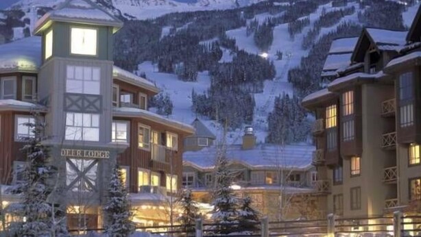 Een met sneeuw bedekte lodge met een opvallende toren en een bord waarop 'DEER RIDGE' staat.