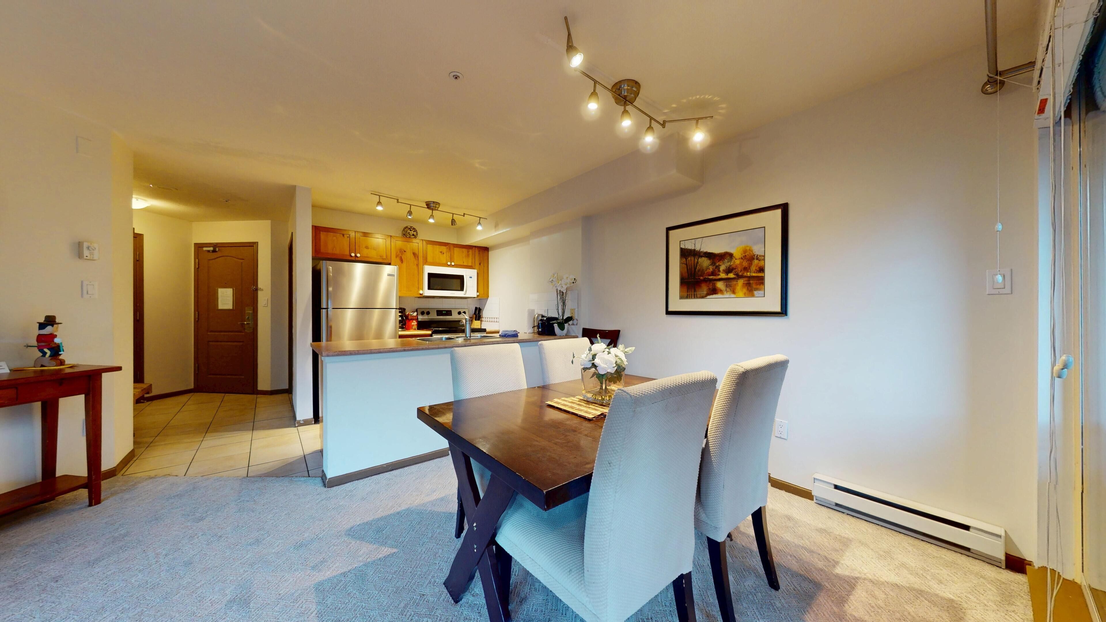 A modern kitchen with a central island, wooden cabinets, and stainless steel appliances.