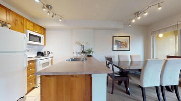Una cocina moderna con armarios de madera, un microondas integrado y una zona de comedor con mesa y sillas.