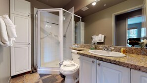 Un baño con ducha, inodoro, lavamanos y armarios.