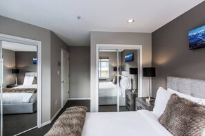 A hotel room with a bed, bedside tables, a mirror, and a television.