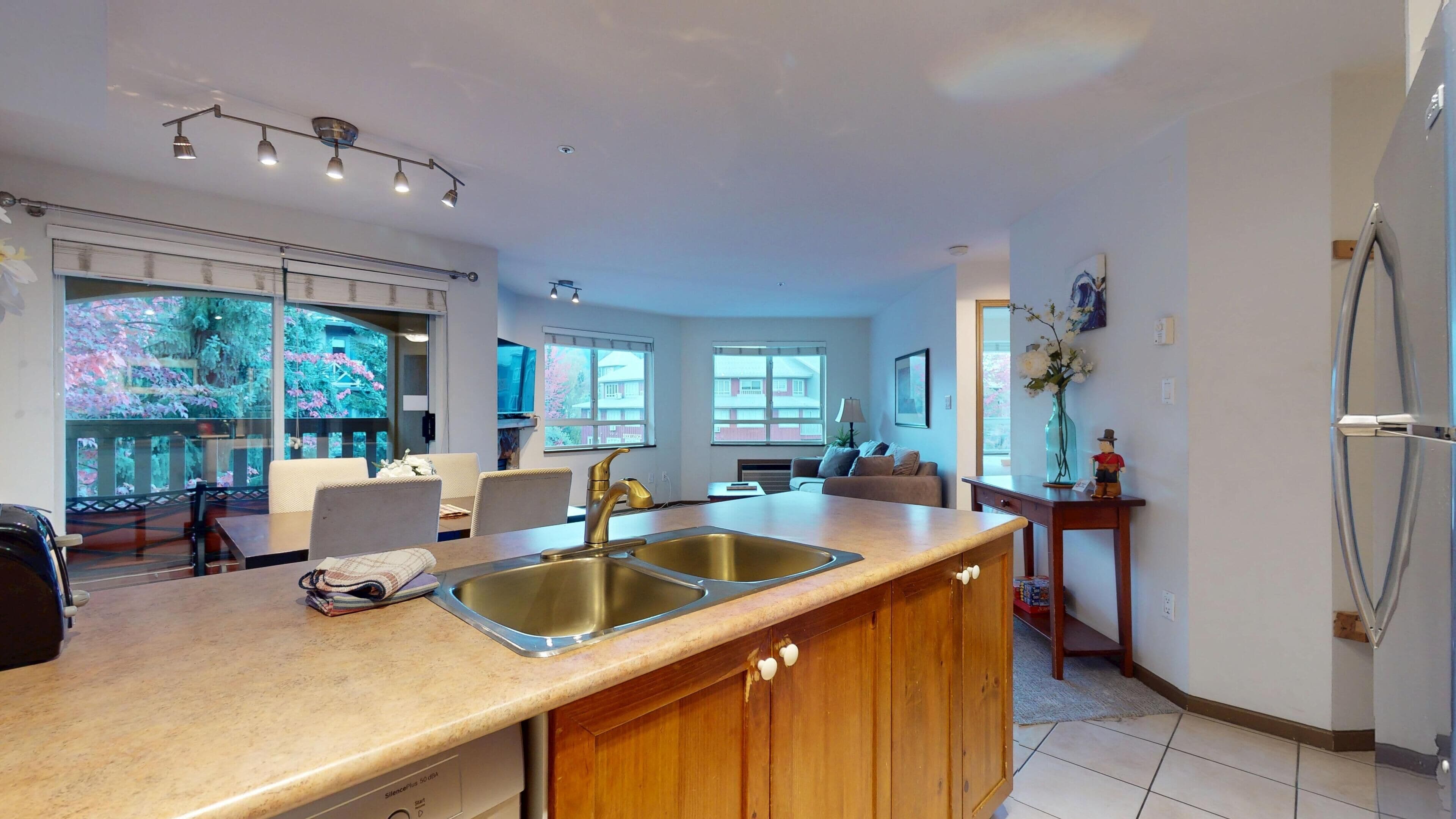 Una cocina moderna con una isla grande, pileta de acero inoxidable e iluminación colgante.
