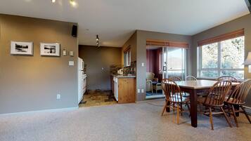 A spacious kitchen with a dining area, featuring a large wooden table and chairs, a built-in oven, and a stone backsplash.