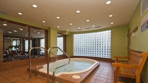 Een wellnessruimte met een jacuzzi, fitnessapparatuur en een houten bank.