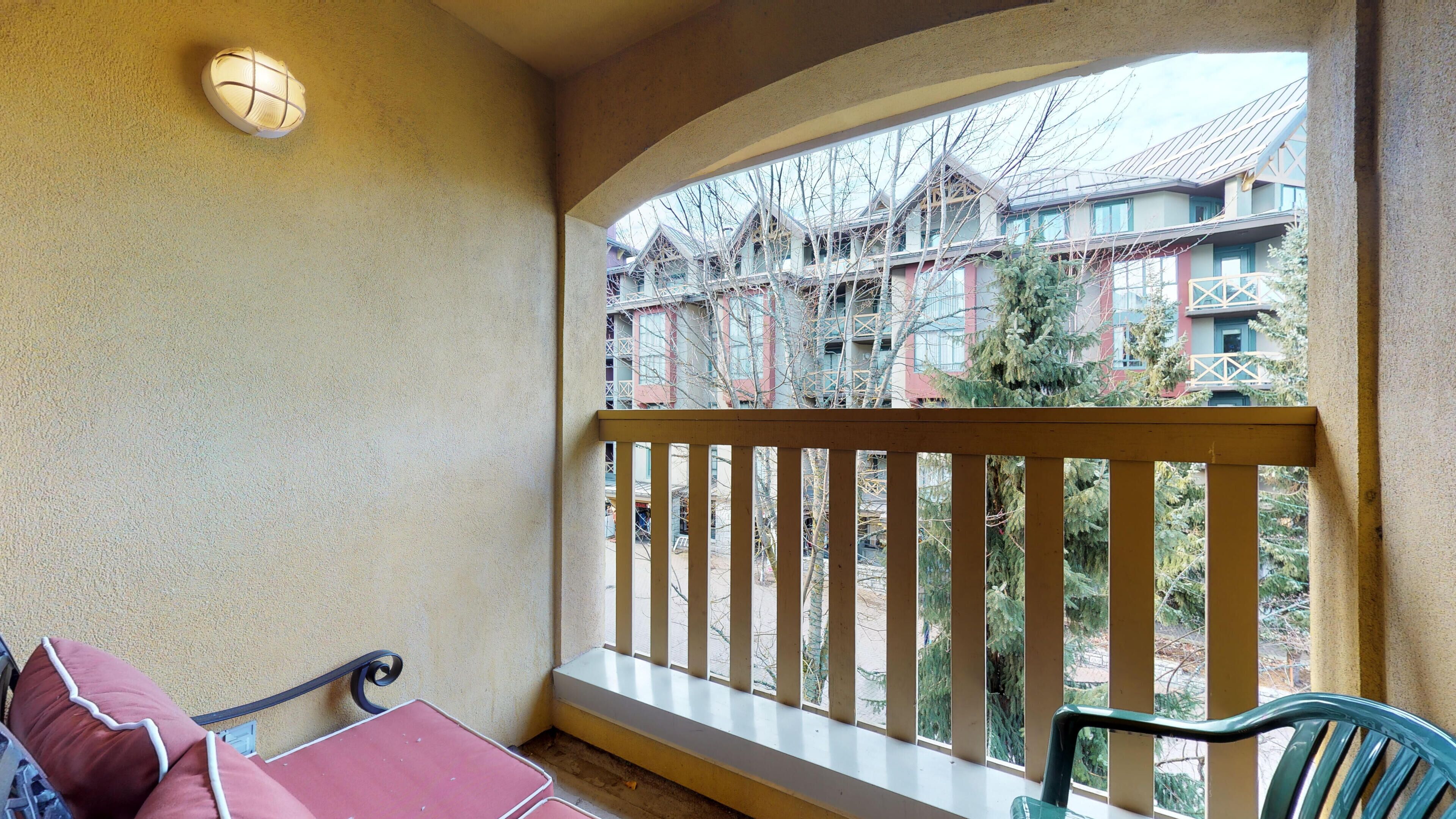 Un balcone con ringhiera in legno, un tavolo con tovaglia rossa e una sedia.