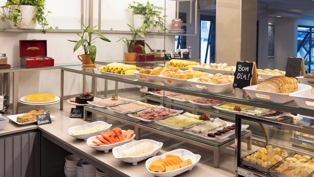 A buffet with various food items and a sign indicating 'Bom Dia'. - Tropikalya Prime Hotel (Balneário Camboriú)
