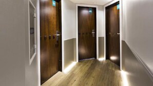 A corridor with wooden doors, white walls, and a wooden floor. - Tropikalya Prime Hotel (Balneário Camboriú)