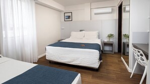 A hotel room with a bed, bedside table, and a desk with a chair. - Tropikalya Prime Hotel (Balneário Camboriú)