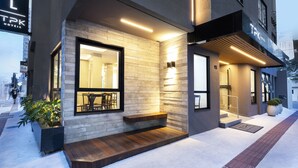 A modern hotel exterior with a prominent entrance, a visible seating area, and a clear view of the interior through the glass doors. - Tropikalya Prime Hotel (Balneário Camboriú)