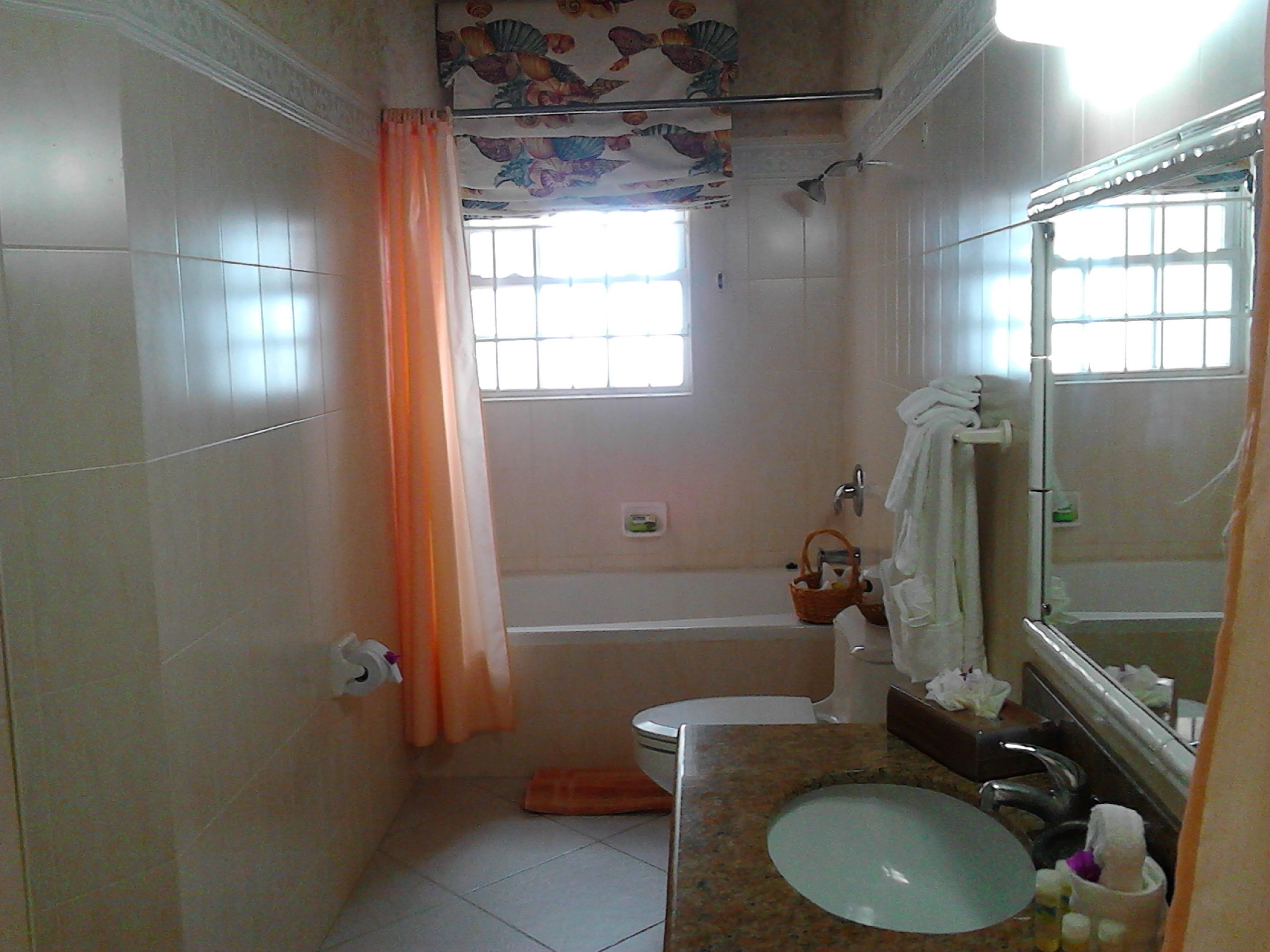 Ein Badezimmer mit Badewanne, Toilette, Waschbecken und einem Fenster mit Vorhang.
