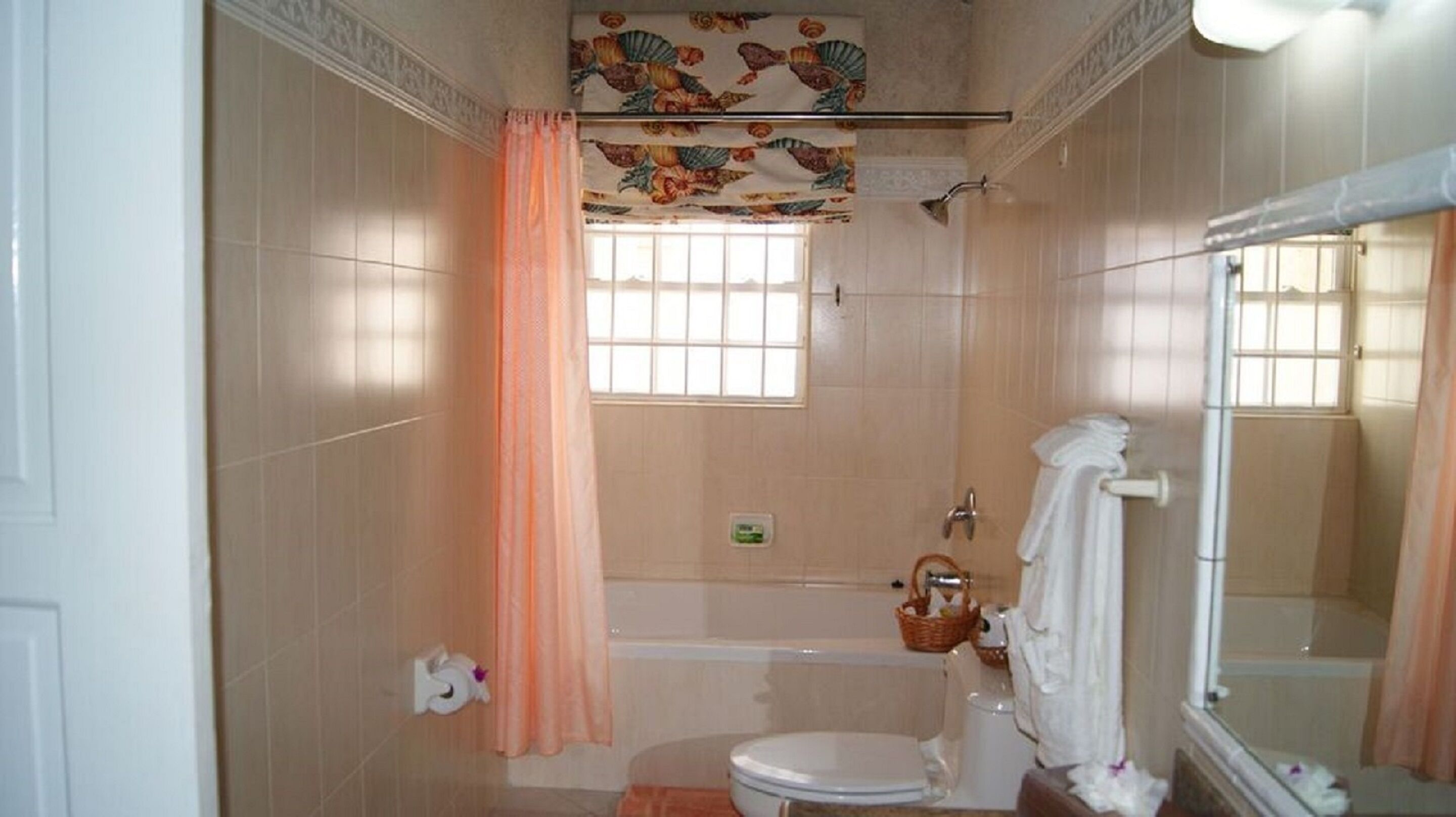 A bathroom with a toilet, a bathtub, a shower, and a window with a curtain.