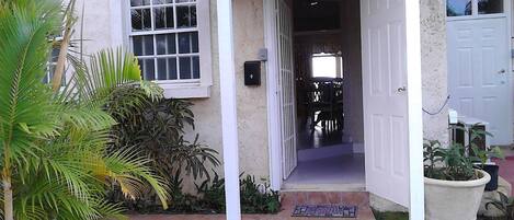 Una entrada de casa con un porche cubierto, una puerta visible y un camino que lleva al interior.