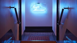 A modern hallway with a neon sign reading "La Casa de la Luna" and a carpeted floor.