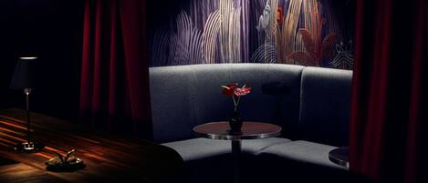 A dimly lit room with a sofa, a small round table with a vase, and a lamp.