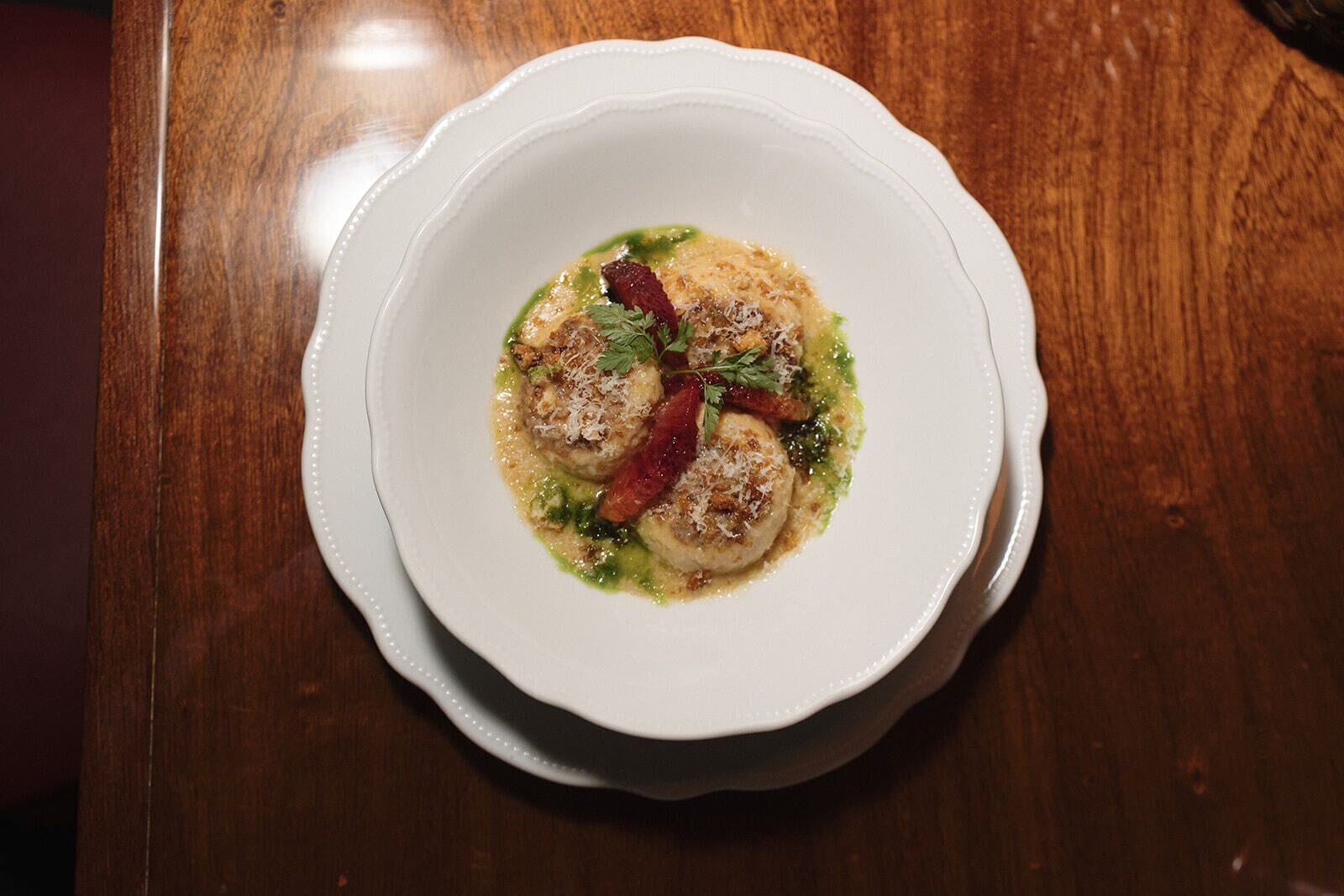 A white plate with a dish on a wooden table.