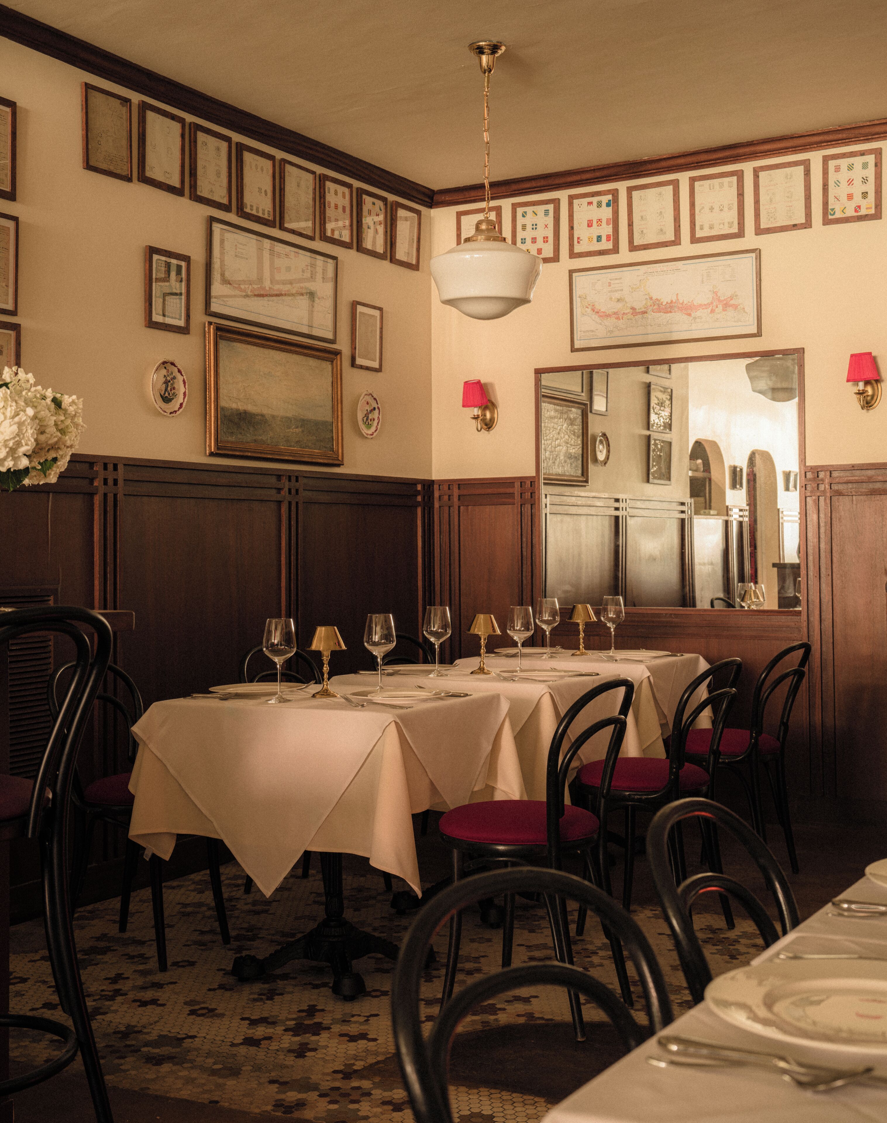 A dining area with tables set for service, framed certificates on the wall, and a mirror reflecting the room.