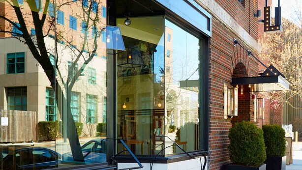 A hotel exterior with a large glass window, a visible staircase, and a sign reading "HOVSE".