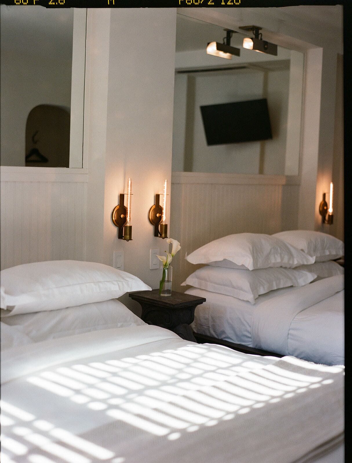 Habitación de hotel con dos camas, un televisor de pantalla plana montado en la pared y apliques de pared.