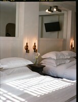 Habitación de hotel con dos camas, un televisor de pantalla plana montado en la pared y apliques de pared.