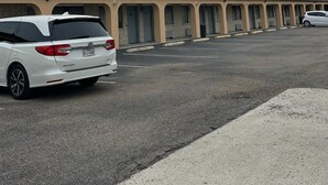 A motel with a row of rooms, a parking lot, and a white car parked in front. - Executive Inn (Robstown)