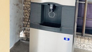 A water dispenser with a digital display, located outdoors near a building entrance. - Executive Inn (Robstown)