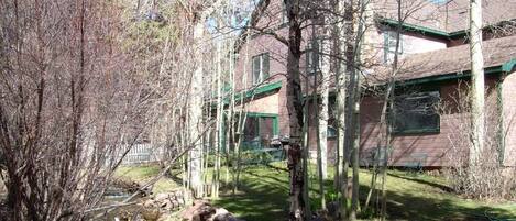 A house with a green roof, a small stream, and a stone wall.