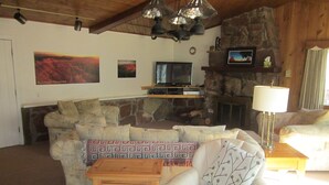 Uma sala de estar acolhedora com lareira de pedra, televisão e um espaço de estar confortável.