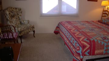 A bedroom with a bed, a chair, and a window.