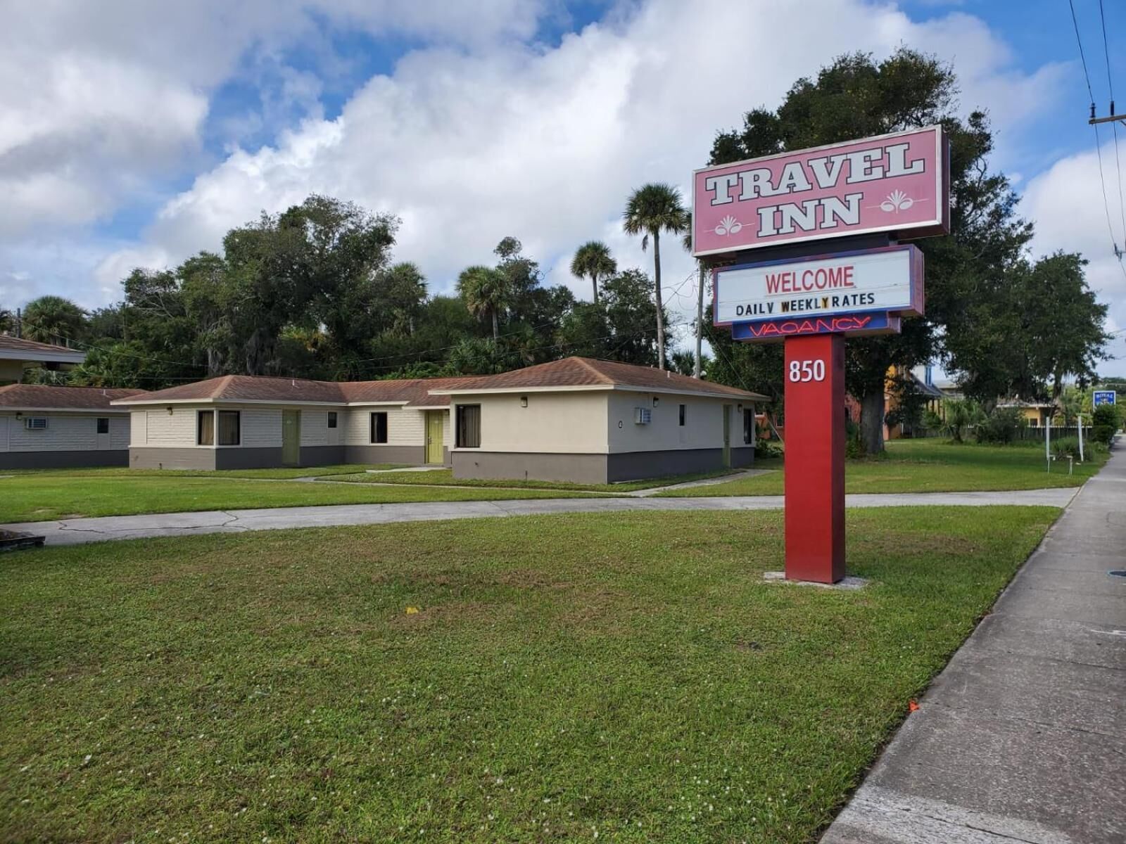 A Travel Inn sign with a welcome message and a vacant rate sign.
