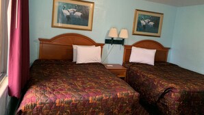 Une chambre d’hôtel avec deux lits, chacun recouvert d’une couvre-lit à motifs. Deux lampes murales sont fixées sur une table de chevet placée entre les lits.