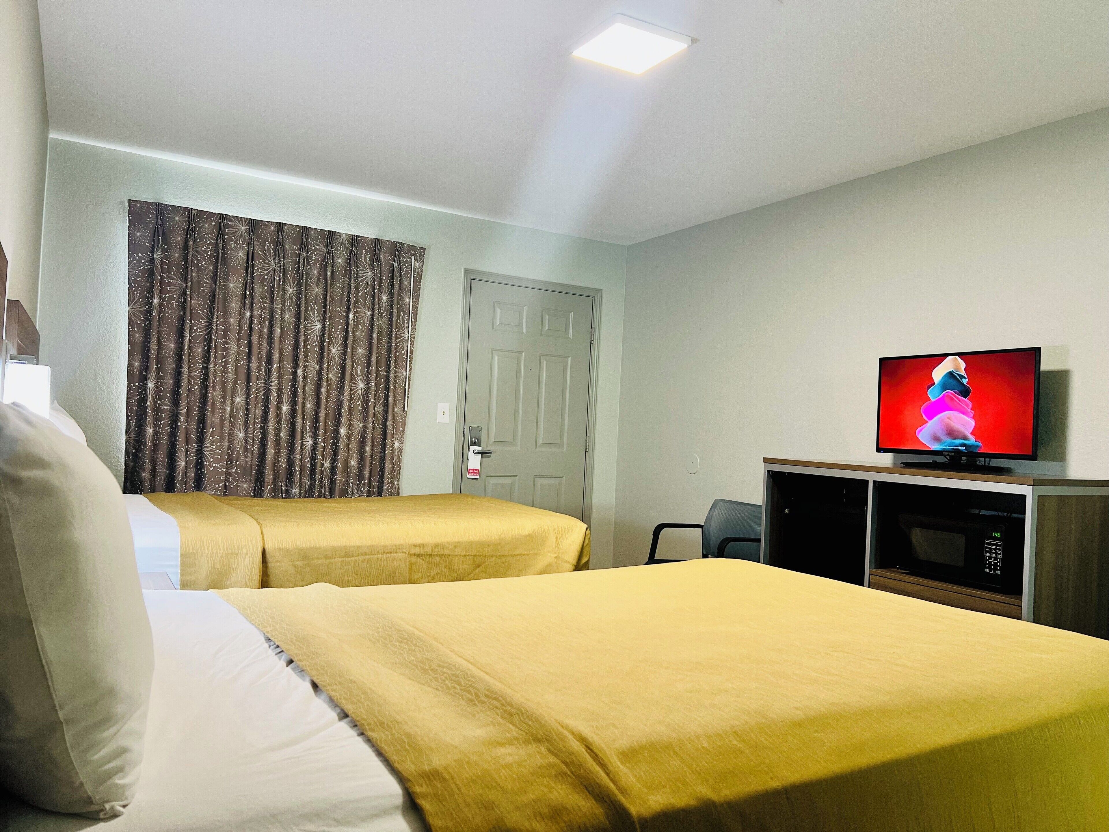 A hotel room with two beds, a television, and a microwave.