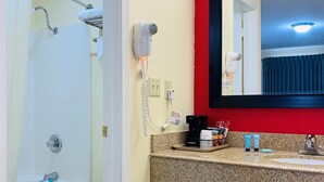 Un baño con ducha, inodoro, lavamanos y un secador de pelo en la pared.