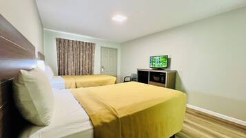 A hotel room with two beds, a television, a door, and a window with curtains.