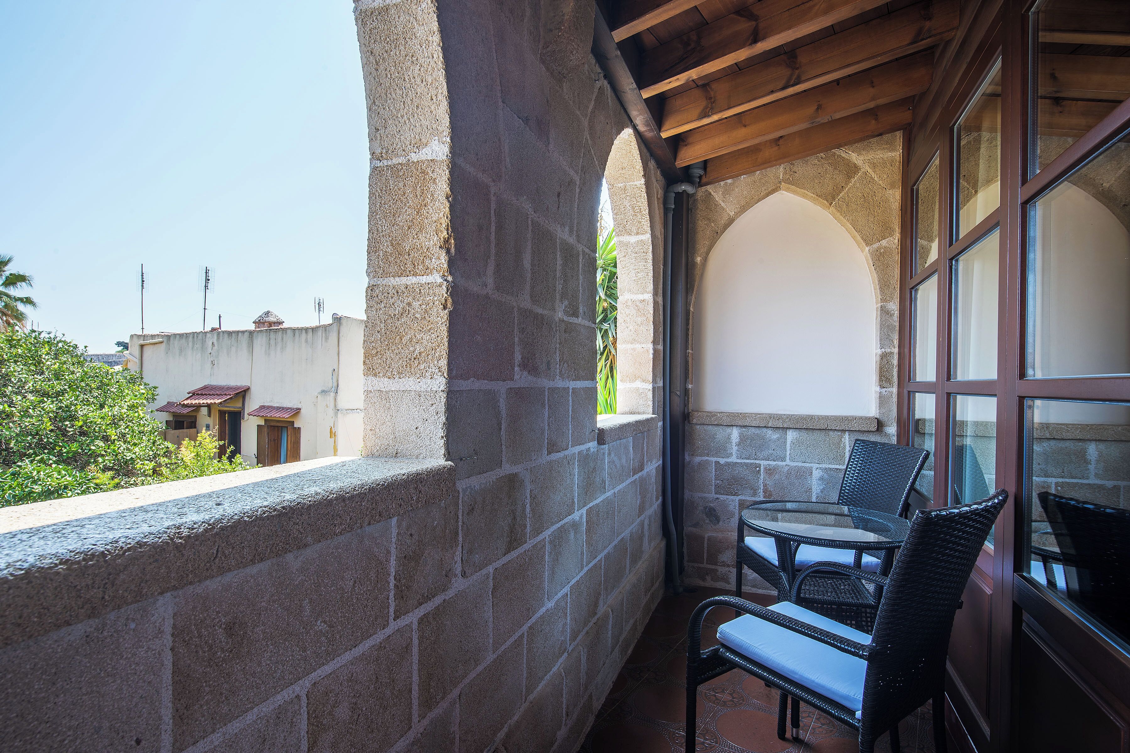 Un balcon avec des murs en pierre, un plafond en bois et une table avec des chaises.