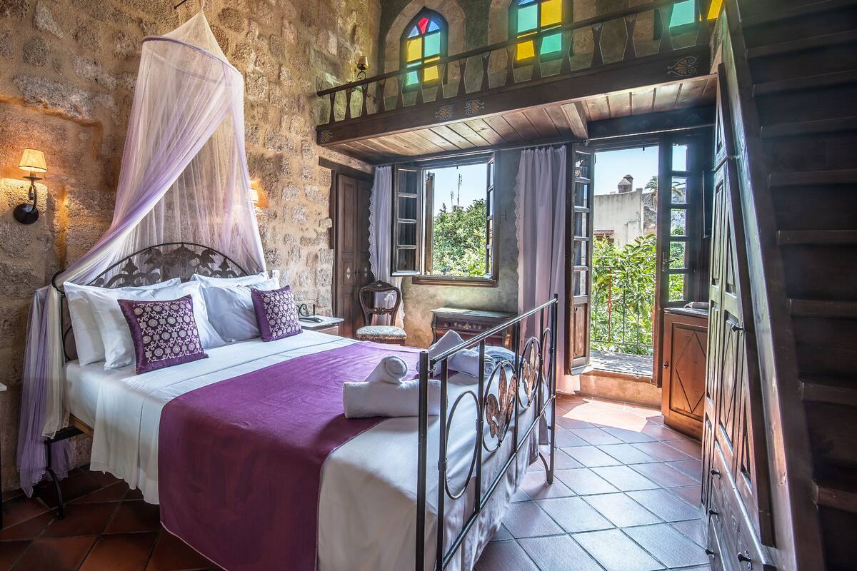 A bedroom with a bed, a chair, a balcony, and a view of the outside.