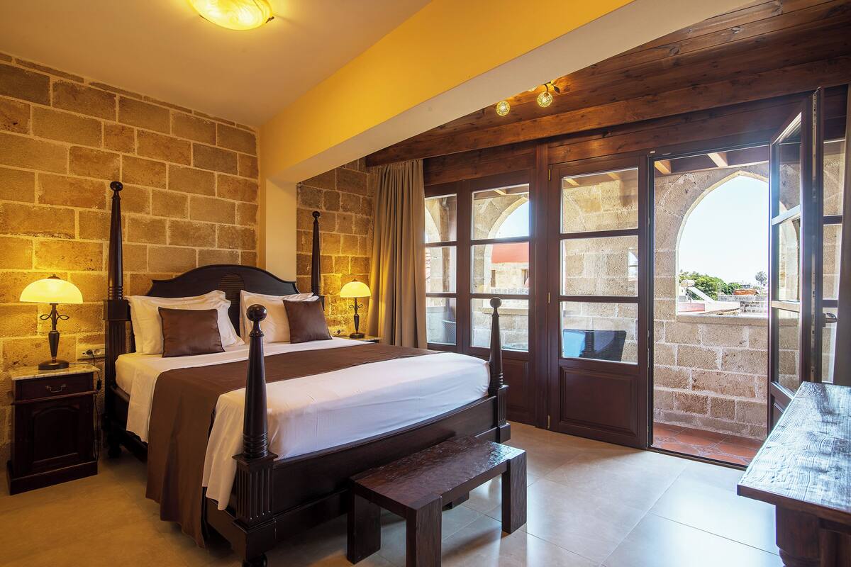 A bedroom with a large bed, wooden headboard, bedside tables with lamps, and a bench.