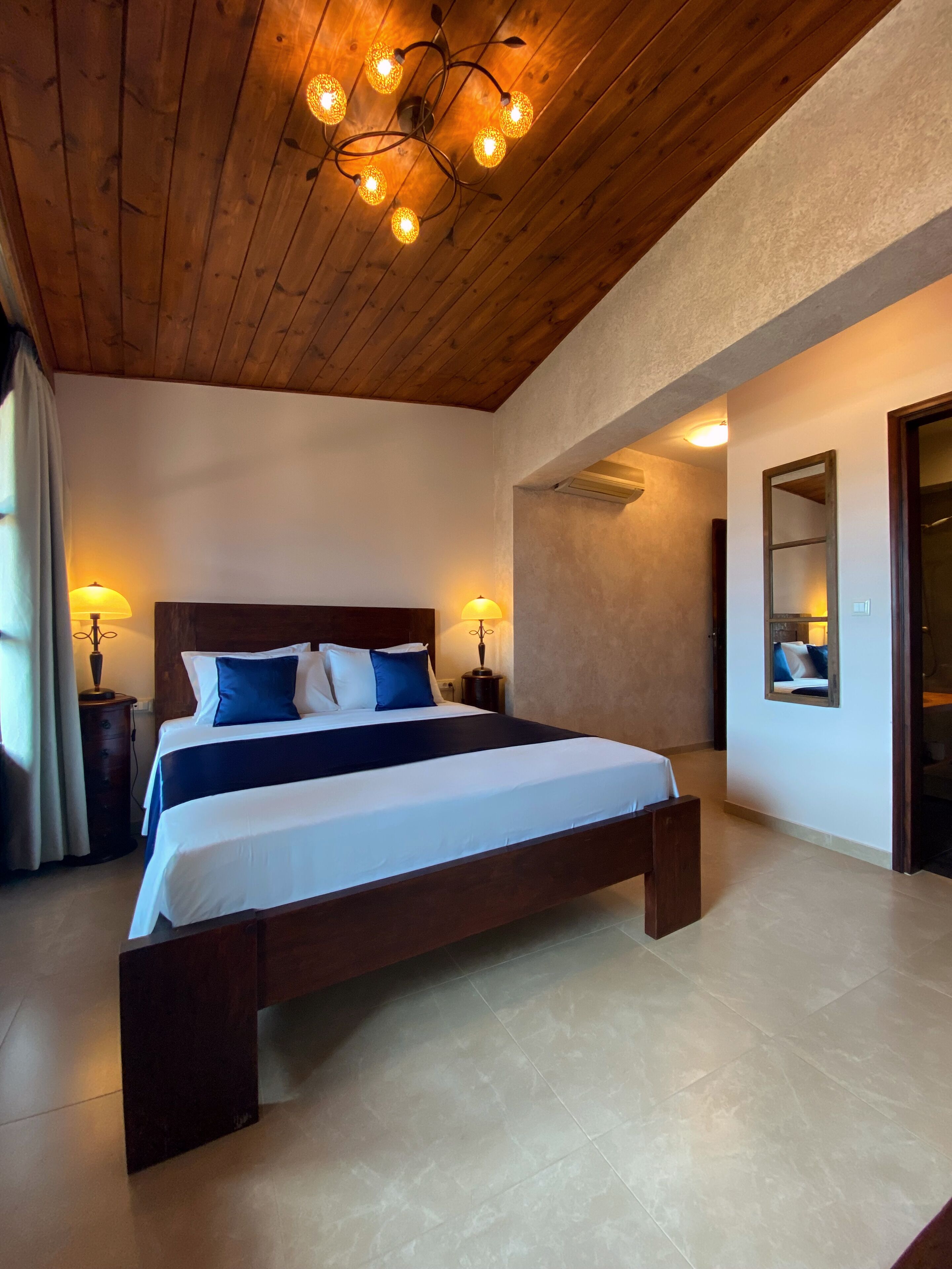 A bedroom with a large bed, wooden ceiling, and two bedside lamps.