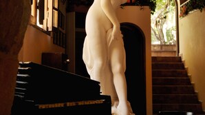 Una estatua de mármol en un pasillo tenuemente iluminado, con una escalera al fondo.