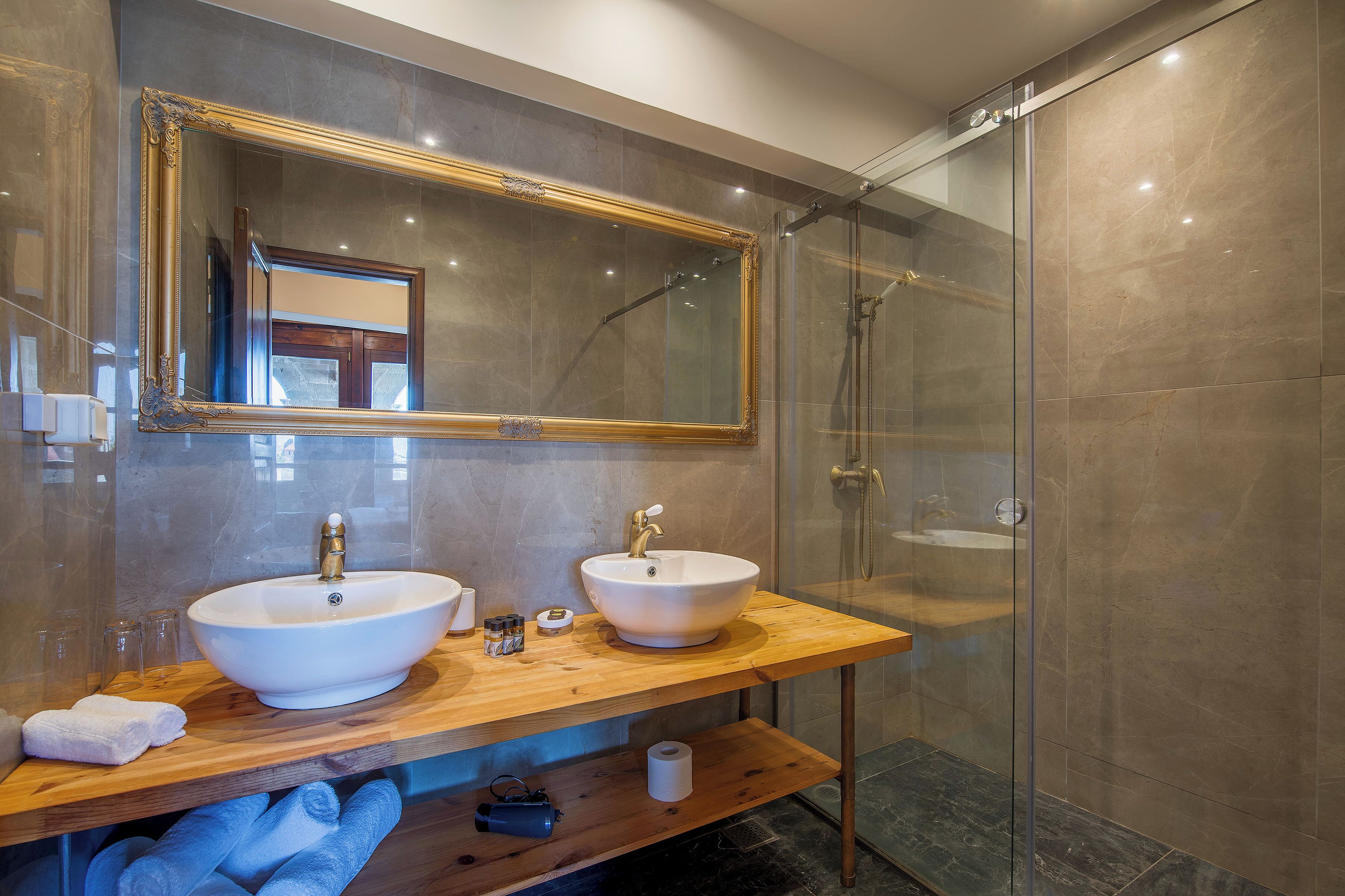 A modern bathroom with two sinks, a large mirror, and a glass shower enclosure.