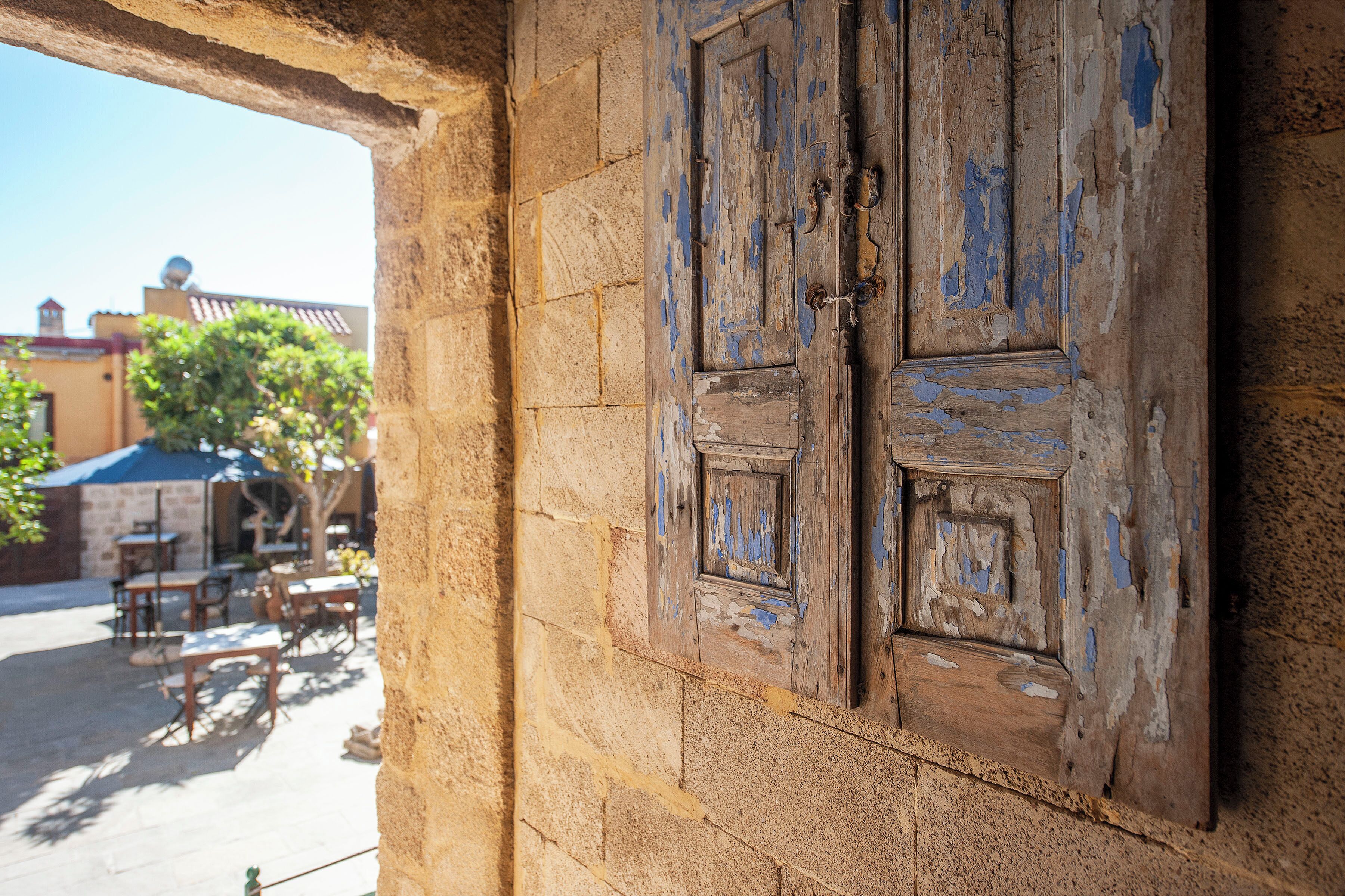 A rustic wooden door with peeling paint, set in a stone wall.