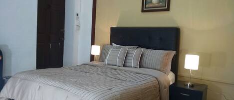 A neatly made bed with a striped bedspread, a dark headboard, and two bedside lamps.