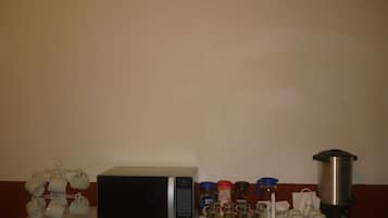 A kitchen area with a microwave, coffee maker, and various coffee and tea containers.