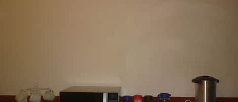 Una cocina con microondas, cafetera y diferentes recipientes para café y té.