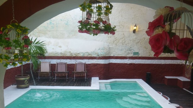 Zona de piscina con interior blanco, terraza de madera y pared roja y blanca.