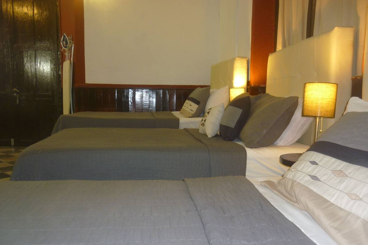 A hotel room with two beds, each with a pillow and a bedside lamp.