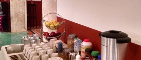 A buffet setup with a variety of food items, a coffee maker, and a cake on a table.