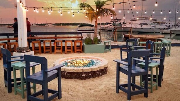 A beachside seating area with a fire pit, wooden benches, and string lights. - Mangrove Marina and Resort Aqualodge Houseboats (Tavernier)